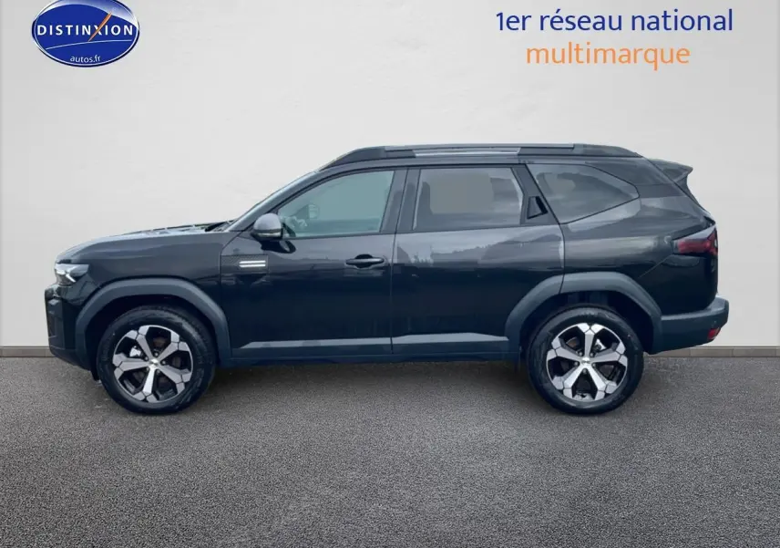 Profil latéral gauche du SUV Dacia Bigster noir 2025 avec jantes alliage diamantées et barres de toit visibles.