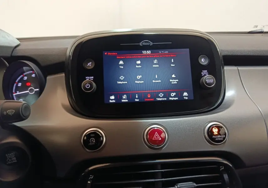Vue rapprochée du tableau de bord de la Fiat 500X 2021, écran tactile central allumé avec commandes autour.