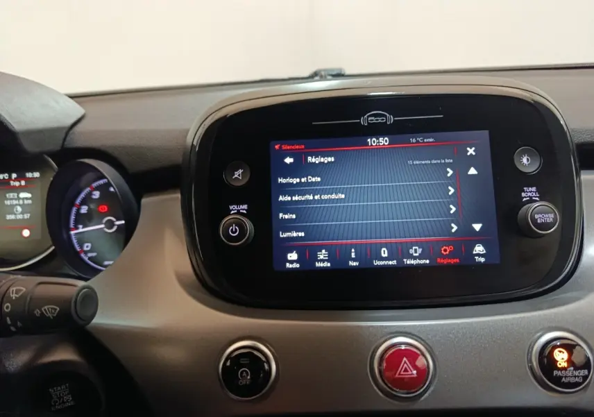 Vue rapprochée du tableau de bord de la Fiat 500X 2021, écran tactile central affichant les réglages, détails en noir et gris.