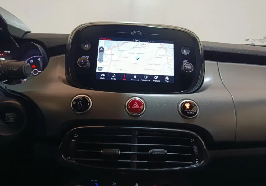 Tableau de bord de Fiat 500X noir avec écran tactile central affichant la navigation, boutons de commande et aérateurs.
