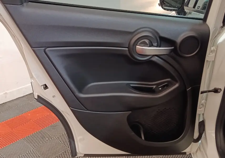 Vue intérieure de la porte arrière droite noire d’un FIAT 500X 2021 avec poignée argentée et commande de vitre.