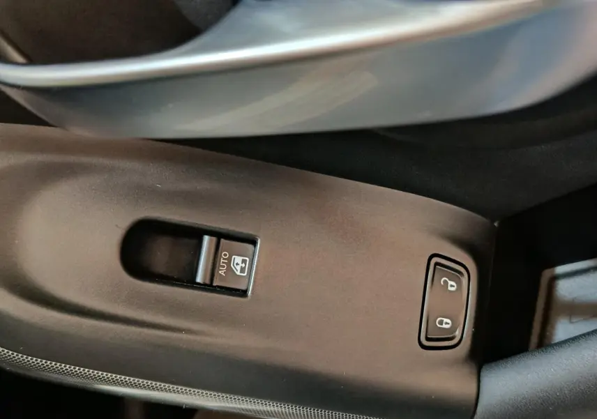 Gros plan sur les commandes de lève-vitre et verrouillage centralisé côté gauche intérieur d'une FIAT 500X noire.