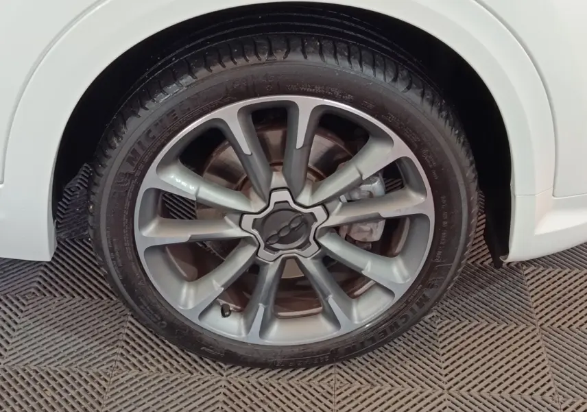 Gros plan sur la roue avant droite d'une FIAT 500X blanche, mettant en valeur la jante alliage au design moderne.