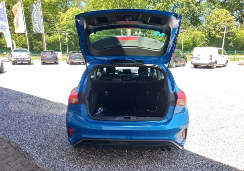 Vue arrière d'une Ford Focus bleue 2019 avec le coffre ouvert, montrant l'espace de chargement et les feux arrière.