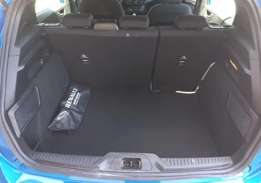 Coffre ouvert vu de l'arrière d'une Ford Focus bleu 2019, avec banquette arrière et sac Renault noir à l'intérieur.