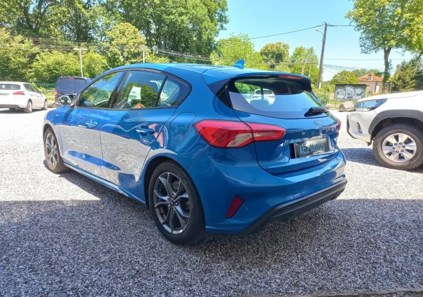 Vue 3/4 arrière droite d'une Ford Focus bleue 2019 version ST-LINE avec jantes alliage et hayon distinctif.