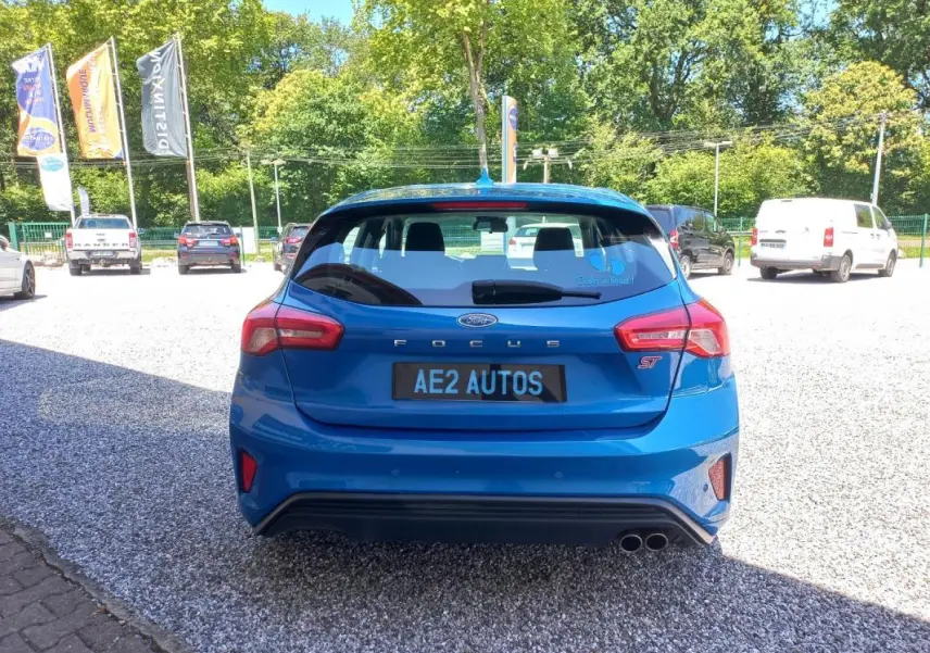 Vue arrière d'une Ford Focus ST-Line bleu vif, avec double sortie d'échappement et logo ST visible.