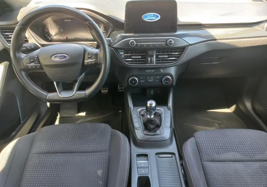 Vue intérieure avant de la Ford Focus 2019 bleu, avec volant multifonctions, écran central et levier de vitesse manuel.