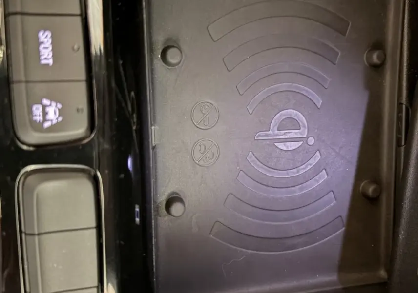 Vue rapprochée de la console centrale de l’Opel Corsa 2025, avec zone de recharge sans fil et boutons de contrôle sport et assistance.
