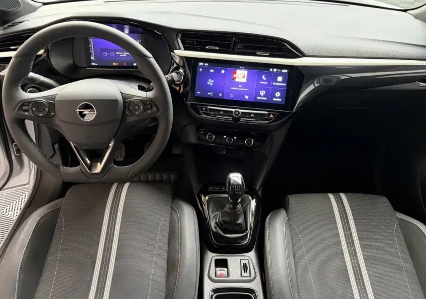 Vue intérieure avant de l’Opel Corsa gris clair 2025, volant multifonctions cuir, écran tactile central et boîte manuelle.