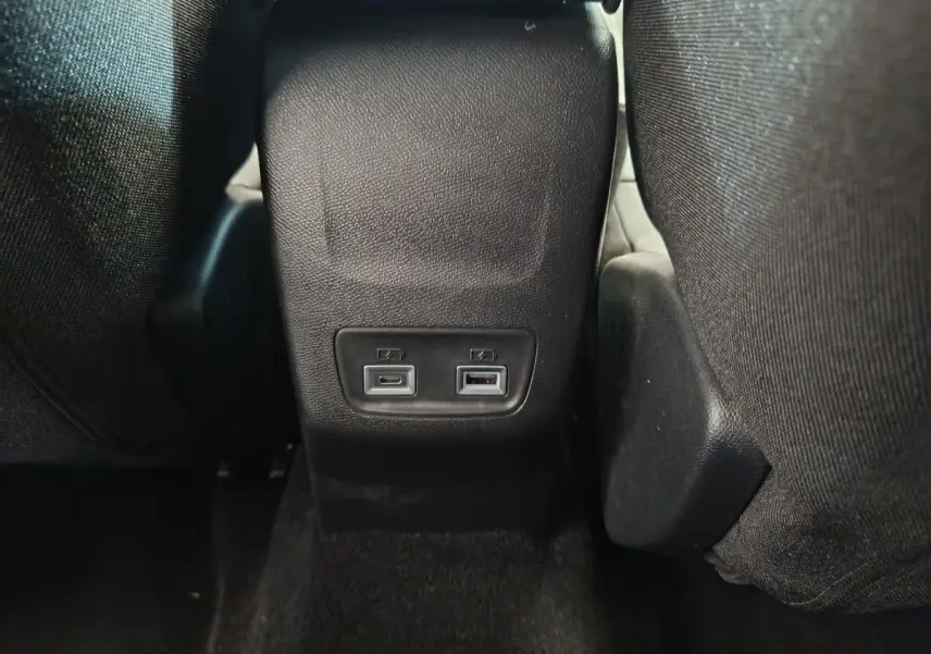 Prise USB avant et arrière vue de près entre les sièges noirs arrière de la Peugeot 208 PureTech 100 S&S Allure 2025.