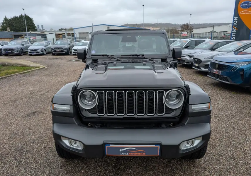 Vue de face du Jeep Wrangler noir avec calandre à sept fentes et phares ronds LED, sur parking extérieur.
