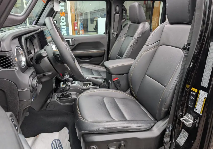 Vue intérieure côté gauche de la Jeep Wrangler 2024 noire, sièges TEP cuir noir avec surpiqûres jaunes visibles.