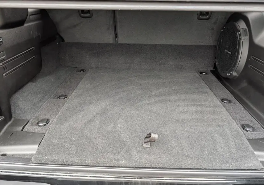 Vue intérieure du coffre noir du Jeep Wrangler 2024 Unlimited Sahara avec caisson de basse Alpine intégré à droite.