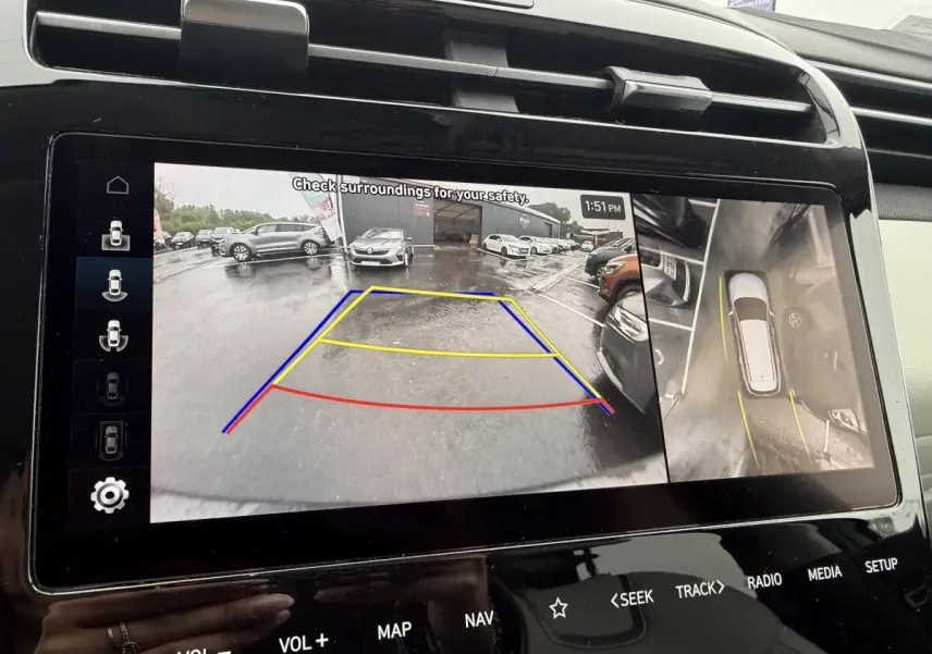 Écran tactile intérieur du Hyundai Tucson 1.6 Hybrid gris foncé montrant la caméra de recul et la vue à 360° en stationnement.