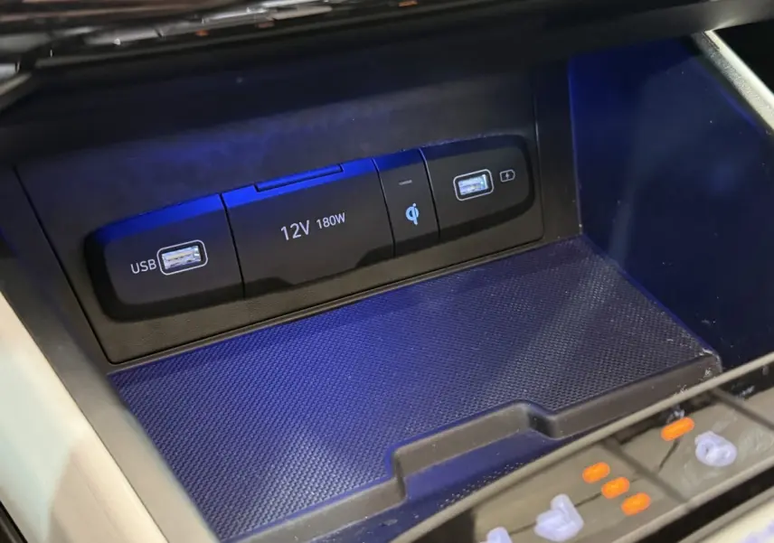 Gros plan sur la zone de recharge à induction avec ports USB et prise 12V du Hyundai Tucson gris foncé 2021.