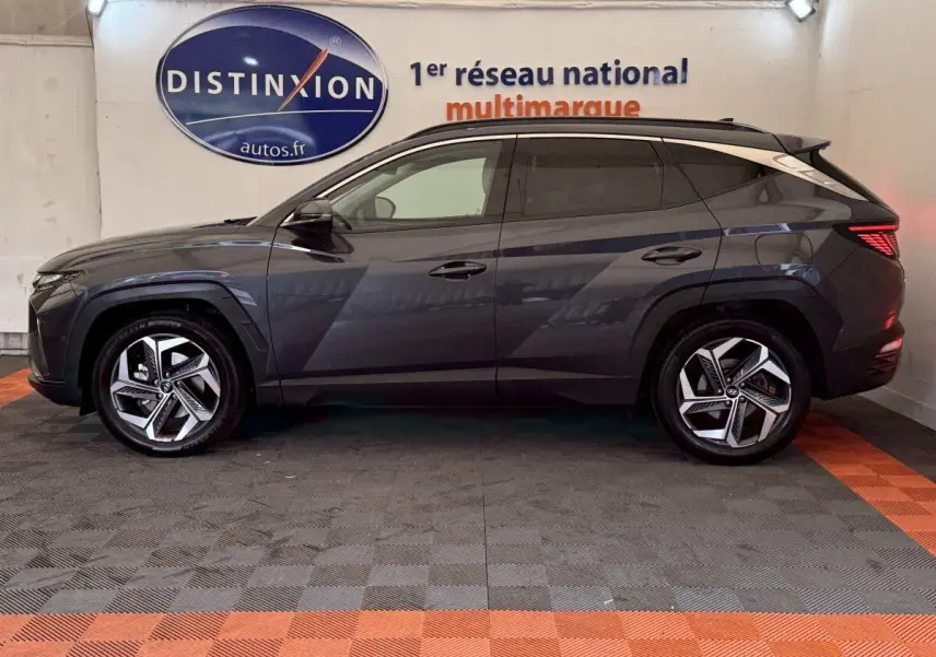 Vue latérale droite du Hyundai Tucson gris foncé 2021 avec jantes alliage et vitres teintées en intérieur showroom.