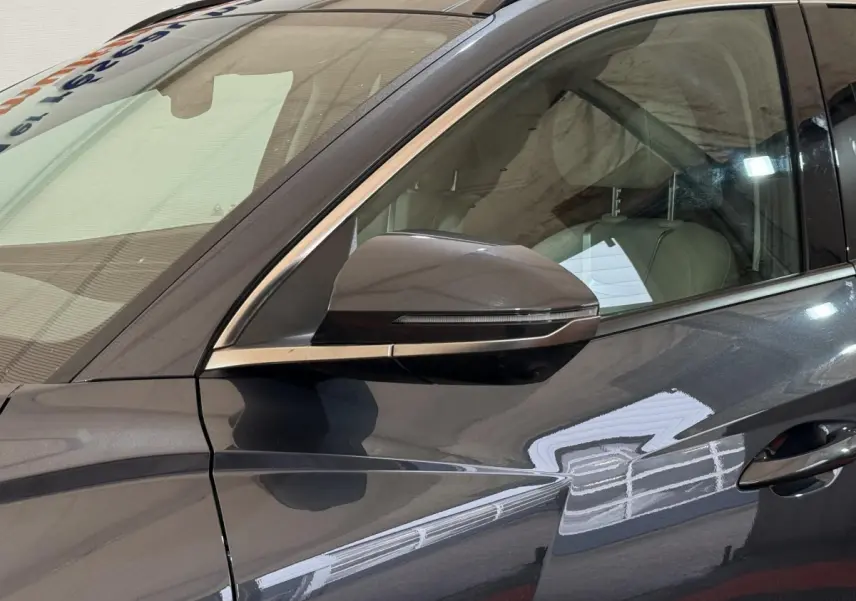Vue rapprochée du côté gauche gris foncé du Hyundai Tucson 1.6 Hybrid 230 Executive avec rétroviseur intégré.