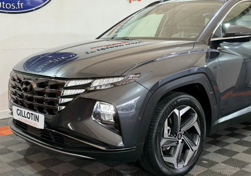 Vue 3/4 avant droit d'un Hyundai Tucson gris foncé avec calandre distinctive et jantes alliage modernes.