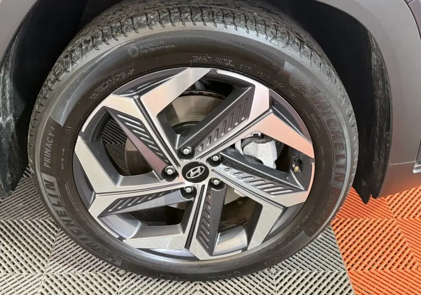 Gros plan sur la jante alliage bicolore et pneu Michelin du côté droit d’un Hyundai Tucson gris foncé.