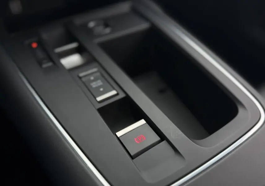 Gros plan sur la console centrale noire du Citroën C5 Aircross avec bouton de frein de stationnement électrique éclairé en rouge.