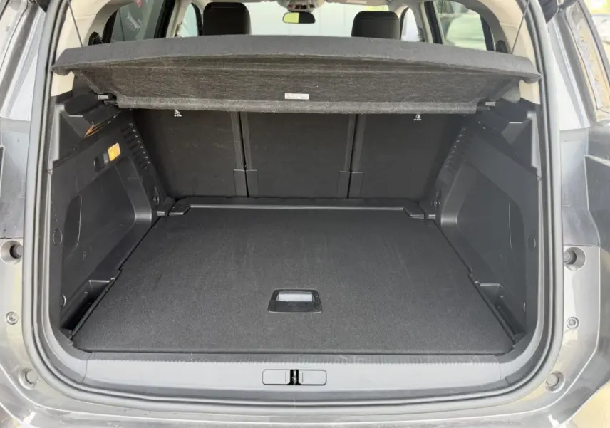Coffre ouvert vu de l’arrière d’un Citroën C5 Aircross gris Platinium, avec plage arrière relevée et intérieur noir.