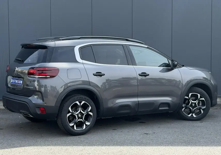 Vue de profil droit du Citroën C5 Aircross gris Platinium avec jantes alliage 18 pouces et barres de toit noires.