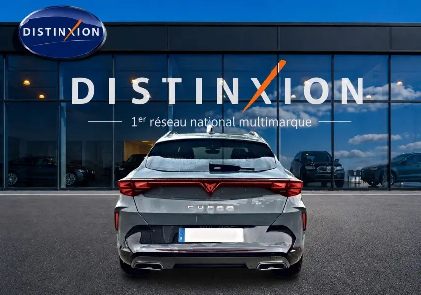 Vue arrière d'un CUPRA Formentor bleu fjord 2026 avec feux LED et double sortie d'échappement, devant un showroom Distinxion.