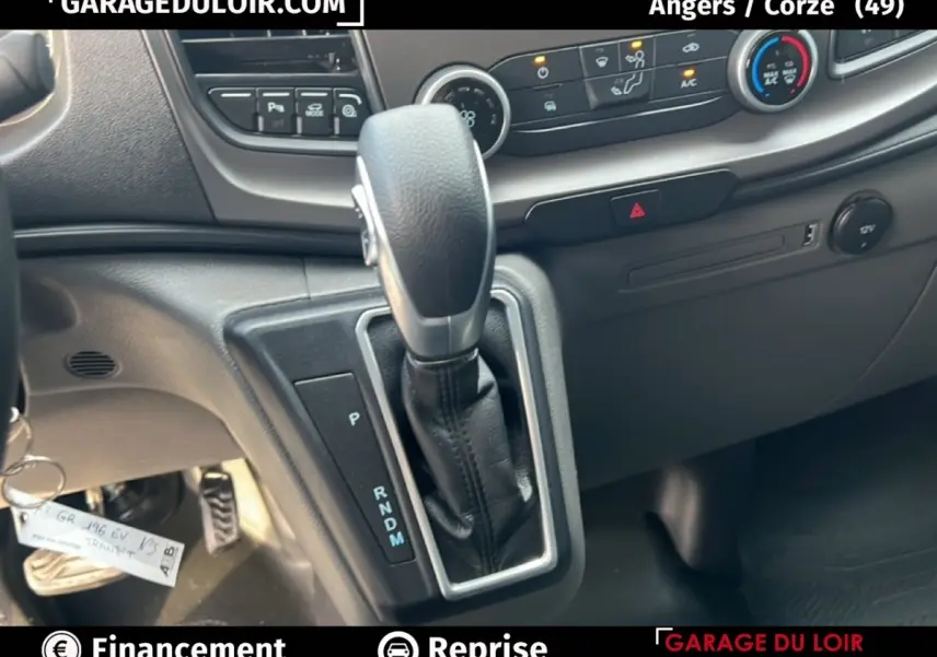 Gros plan sur le levier de vitesses automatique et la console centrale du Ford Transit Custom blanc, intérieur noir.
