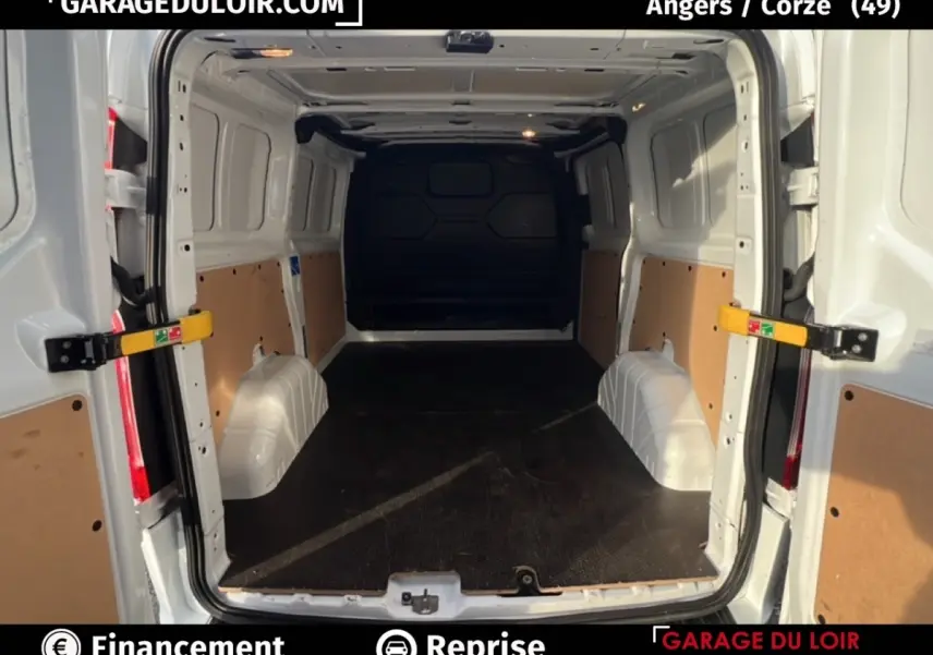Vue intérieure arrière du Ford Transit Custom blanc 2023 avec espace de chargement vide et cloison pleine.