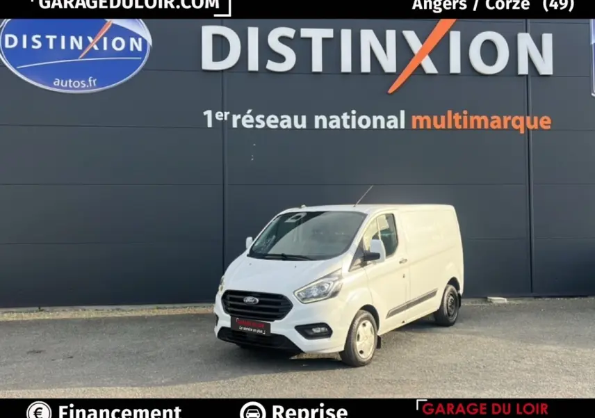 Ford Transit Custom Fourgon blanc en 3/4 avant droit, stationné devant un mur gris avec logo Distinxion.