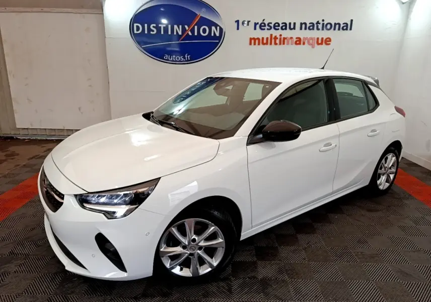 Vue 3/4 avant d'une Opel Corsa blanche 2023 avec jantes alliage et rétroviseurs noirs en intérieur showroom.