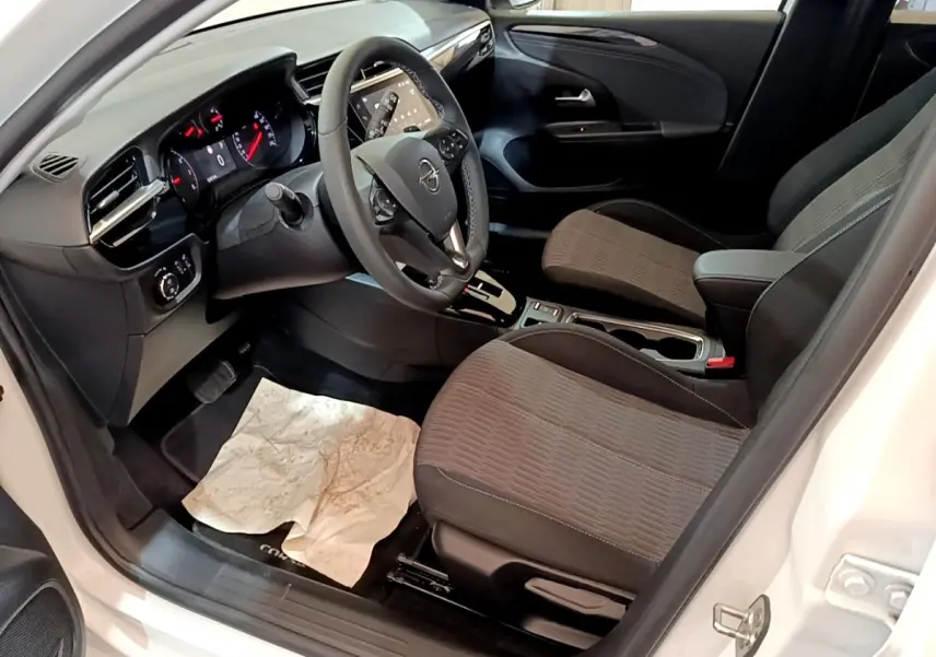 Vue intérieure côté conducteur de l’Opel Corsa blanc 2023, avec tableau de bord digital et sièges tissu gris.