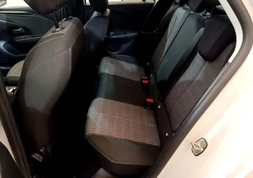 Vue intérieure depuis la porte arrière droite sur la banquette arrière tissu gris et noir de l’Opel Corsa blanc.
