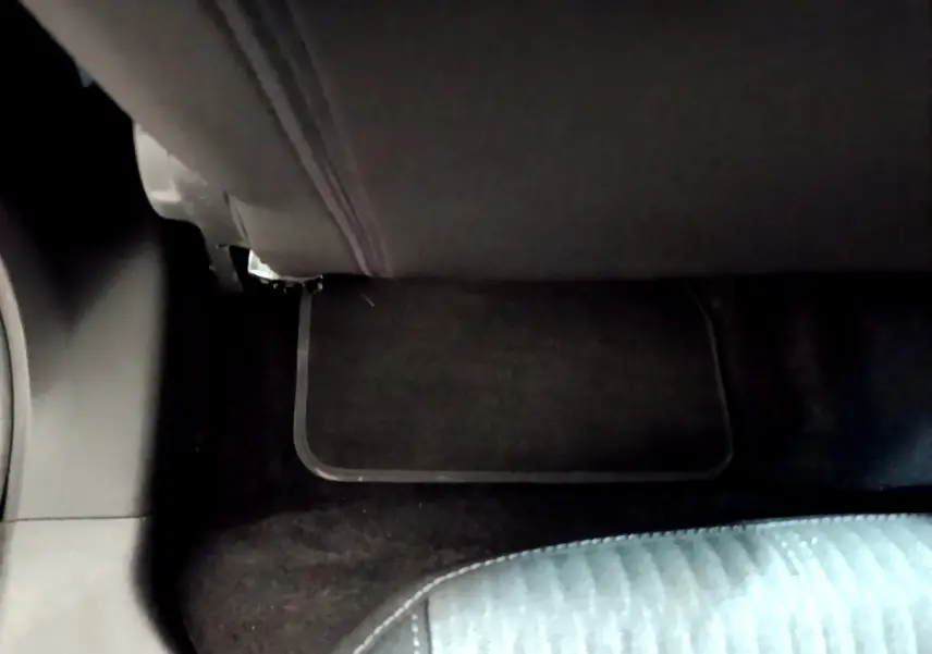 Détail de la moquette et tapis de sol noir sous la banquette arrière d’une Opel Corsa blanche 2023.
