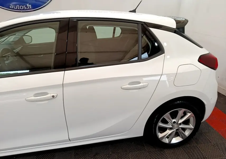 Vue latérale côté droit d'une Opel Corsa blanche avec jantes alliage et spoiler de toit visible.