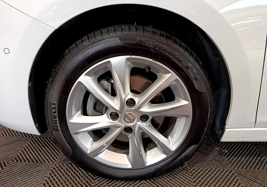 Gros plan sur la roue avant droite d’une Opel Corsa blanche, avec jante alliage argentée et pneu Pirelli.