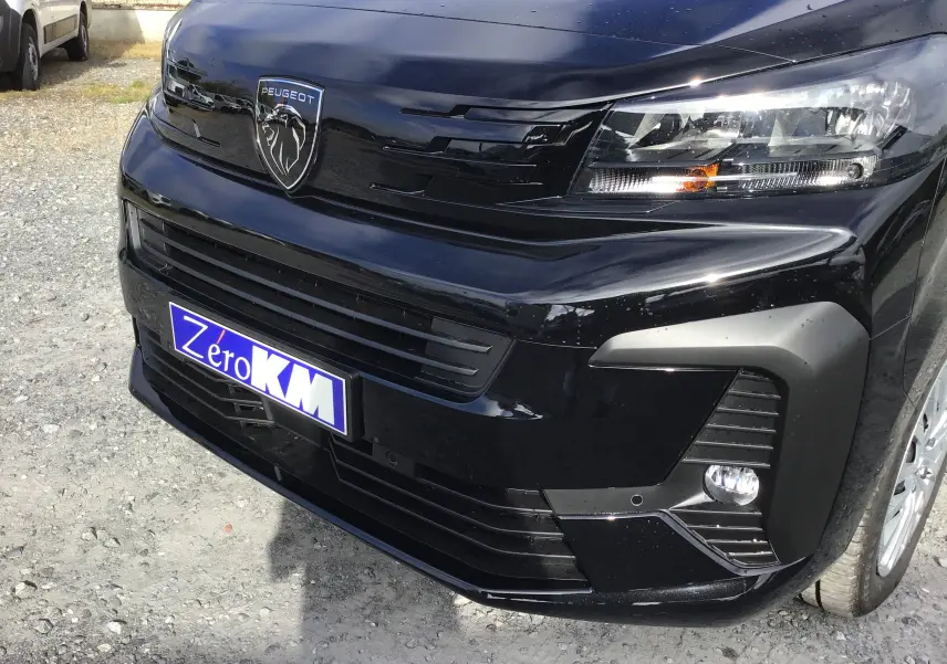 Gros plan sur l’avant droit noir du Peugeot Expert Cabine Approfondie avec logo lion et phares allumés.