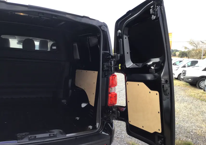 Vue arrière ouverte du Peugeot Expert XL noir, montrant l’espace de chargement avec panneaux de protection en bois sur les portes.