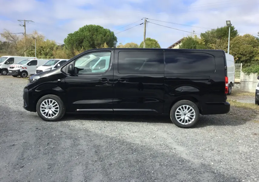 Profil côté gauche d’un Peugeot Expert cabine approfondie noir, avec jantes alliage et vitres teintées, sur un parking extérieur.