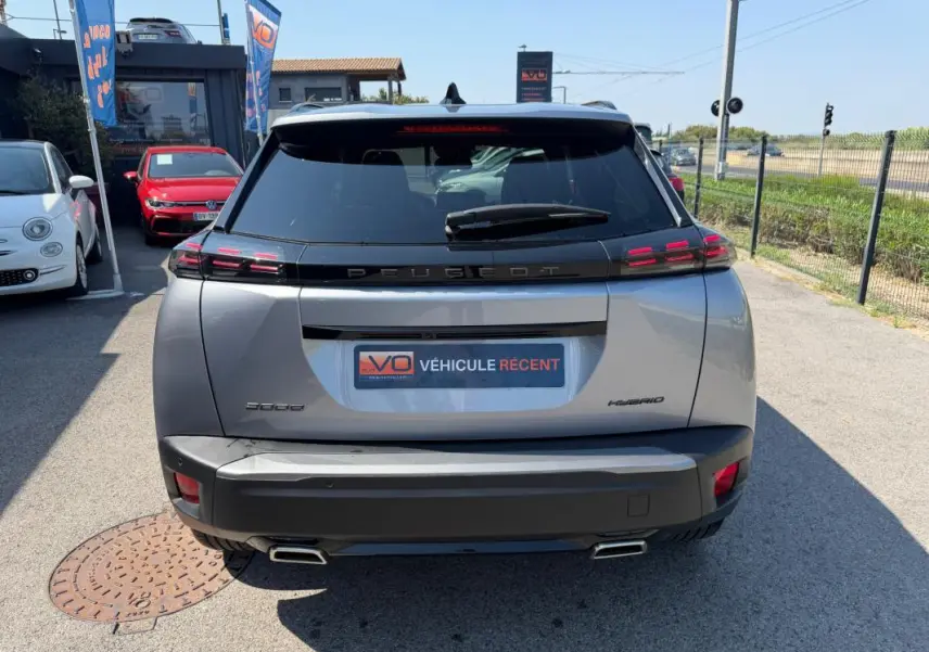 Vue arrière d'un Peugeot 2008 Hybrid gris 2025 avec feux arrière LED et double sortie d'échappement carrée.