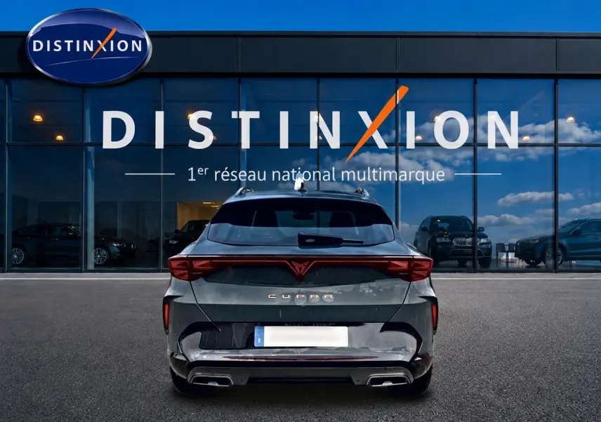 Vue arrière d'une CUPRA Formentor bleu fjord 2026 avec feux LED et double sortie d'échappement, devant un showroom Distinxion.