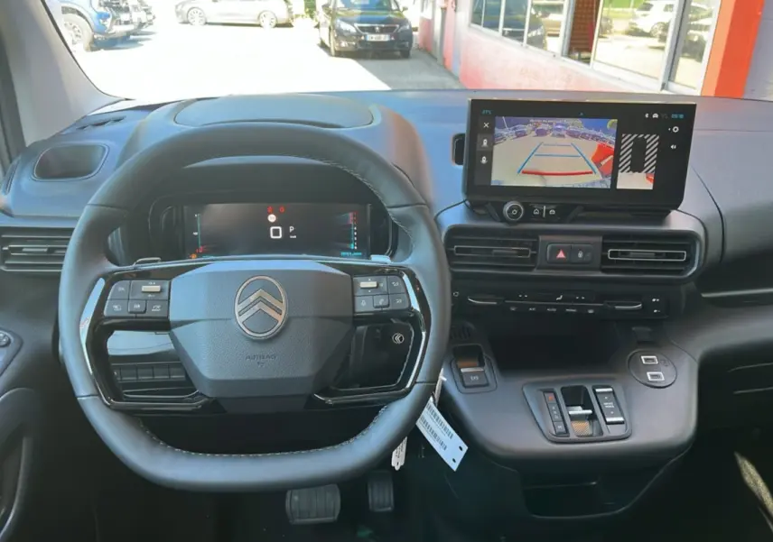 Intérieur du Citroën Berlingo 2025, vue du poste de conduite avec volant cuir et écran tactile affichant la caméra de recul.