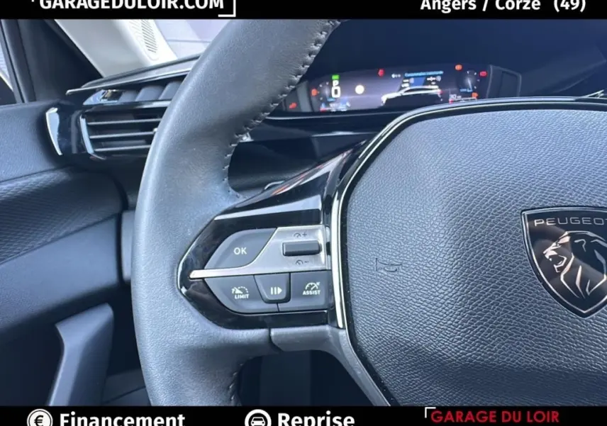 Gros plan sur le volant cuir noir de la Peugeot 308 2023, avec commandes multifonctions et tableau de bord numérique.
