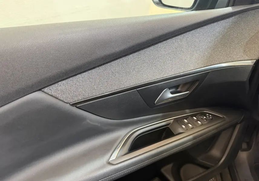 Détail de la porte côté conducteur du Peugeot 3008 vert 2020, avec commandes électriques et insert tissu gris.