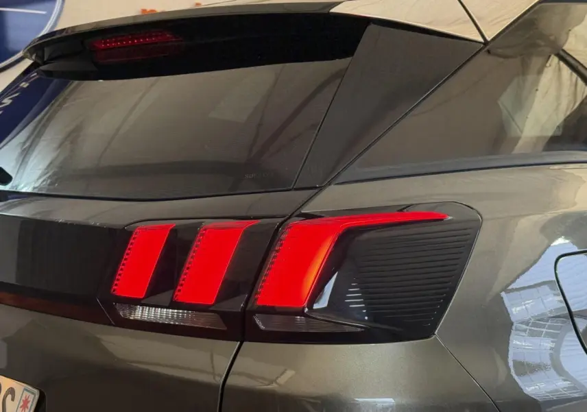 Gros plan sur le feu arrière droit rouge du Peugeot 3008 vert, vue arrière en légère contre-plongée.