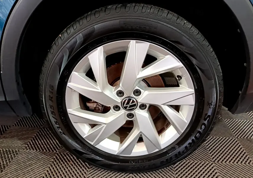 Gros plan sur la roue avant droite du Volkswagen Tiguan bleu, avec jante alliage argentée et logo VW central.