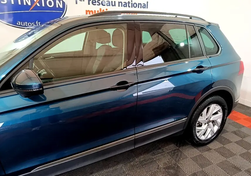 Vue latérale droite d'un Volkswagen Tiguan bleu 2021 avec jantes alliage et rétroviseurs électriques.