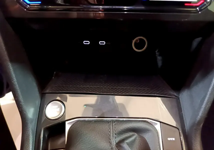 Gros plan sur la console centrale du Volkswagen Tiguan bleu, avec bouton démarrage et levier de vitesse en cuir.