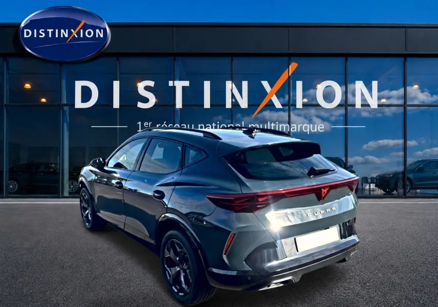 Vue 3/4 arrière droite du CUPRA Formentor bleu fjord avec feux arrière LED et jantes 18 pouces devant un showroom Distinxion.